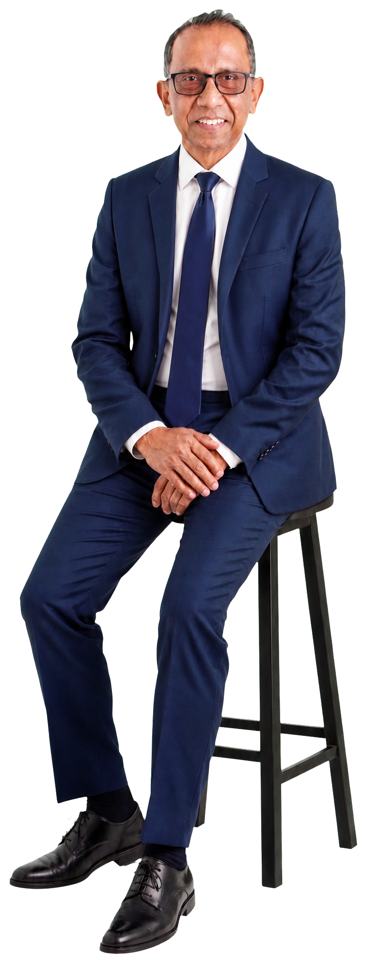 Nalin Wijetilleke seated on a stool in an unbuttoned navy suit and looking directly at the camera